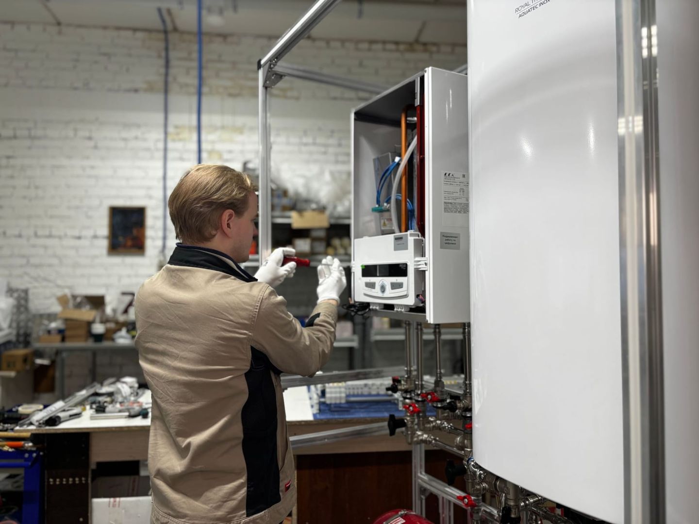 Techniker prüft eine geöffnete wandhängende Heizungseinheit in einer Werkstatt