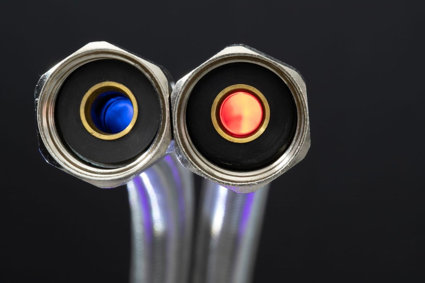 Zwei flexible Panzerschläuche mit blauem und rotem Markierungsring vor dunklem Grund